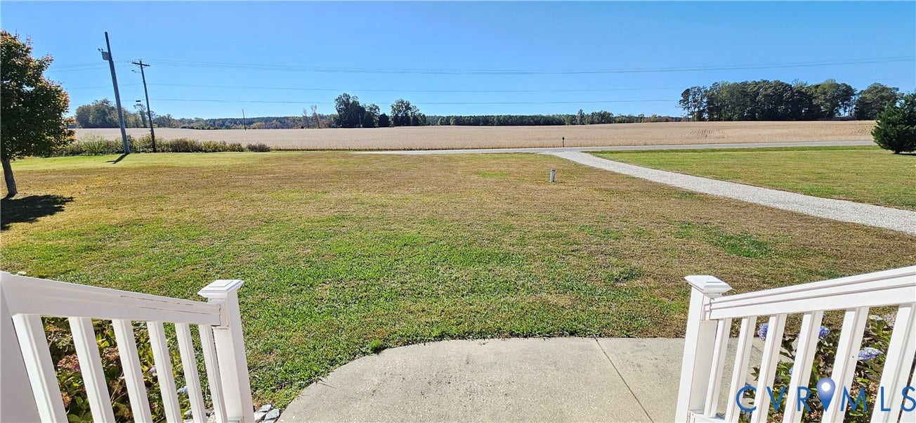 8605 Howerton Road, Center Cross, VA 22437 White vinyl staircase railing overlooking an expansive lawn, concrete walkway, and open agricultural land