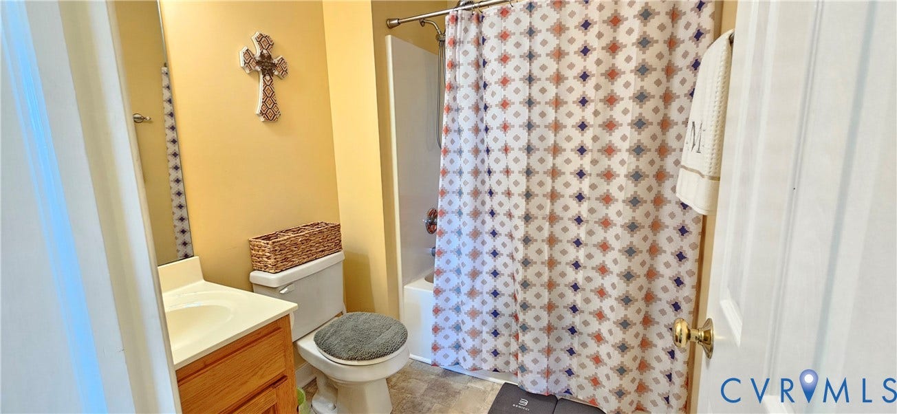 8605 Howerton Road, Center Cross, VA 22437 Bathroom featuring a wood-finish vanity with a molded countertop, a built-in wall mirror, a ceramic toilet, and a bathtub-shower combination with a surround