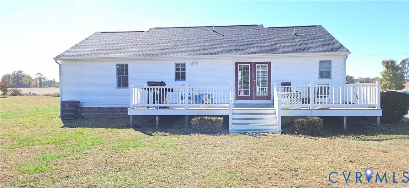 8605 Howerton Road, Center Cross, VA 22437 Rear exterior featuring white vinyl siding, a raised white deck with stairs, double glass-panel doors, and brick foundation detailing
