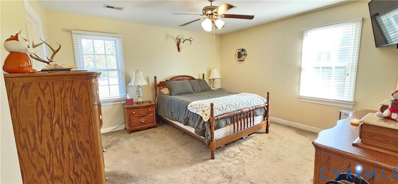 8605 Howerton Road, Center Cross, VA 22437 Neutral-toned room featuring neutral carpeting, multi-pane windows with integrated blinds, and a ceiling-mounted fan with light fixture