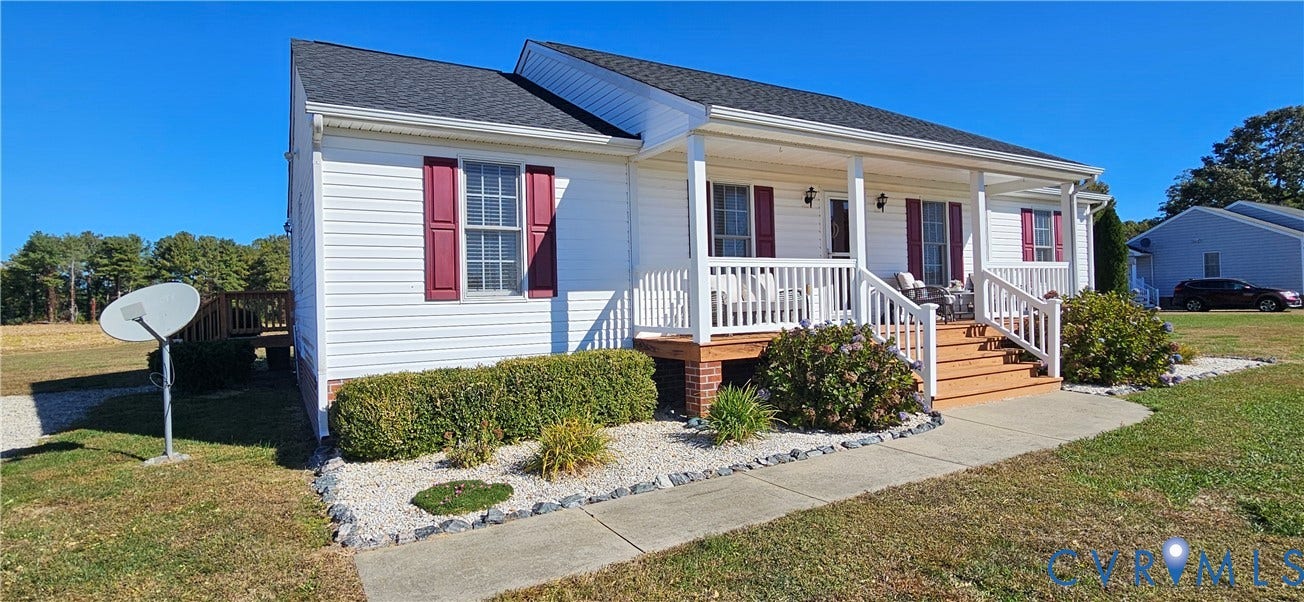 8605 Howerton Road, Center Cross, VA 22437 Single-story residence featuring white horizontal siding, a covered front porch with white railing, and decorative red window shutters