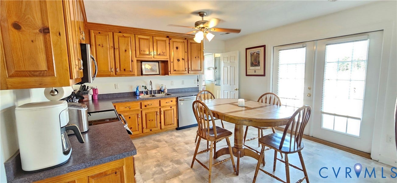 8605 Howerton Road, Center Cross, VA 22437 Kitchen featuring knotty wood cabinetry, dark laminate countertops, stainless steel dual-basin sink, integrated ceiling fan, and paneled glass exterior doors