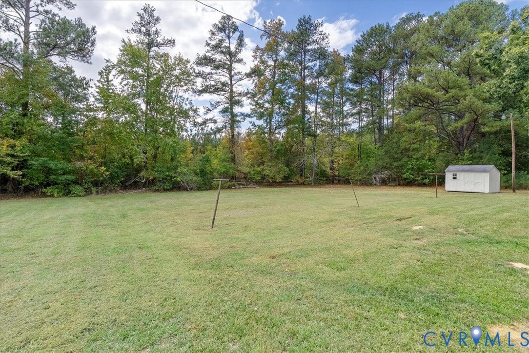 4942 Pleasant Shade Drive, Emporia, Emporia, VA 23847 Expansive backyard featuring a level lawn, mature tree line, and detached storage building