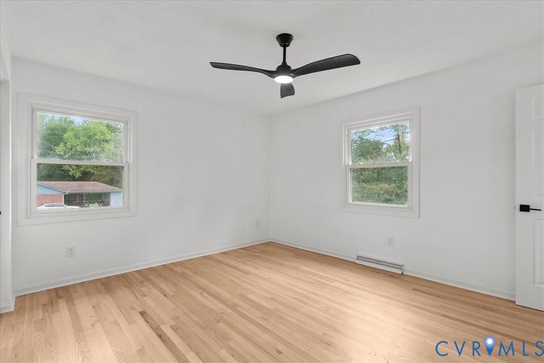 4942 Pleasant Shade Drive, Emporia, Emporia, VA 23847 Neutral-toned room featuring light wood-finish flooring, white walls, dual windows, and a matte black ceiling fan with an integrated light fixture