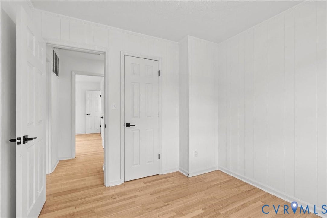 4942 Pleasant Shade Drive, Emporia, Emporia, VA 23847 Interior space featuring white vertical paneling, wood-finish flooring, and six-panel interior doors with matte black hardware