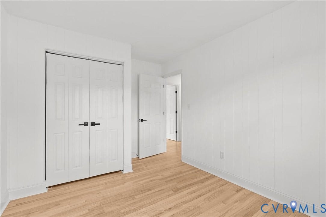 4942 Pleasant Shade Drive, Emporia, Emporia, VA 23847 Room featuring white vertical-panel walls, wood-finish flooring, and white interior doors with matte black hardware