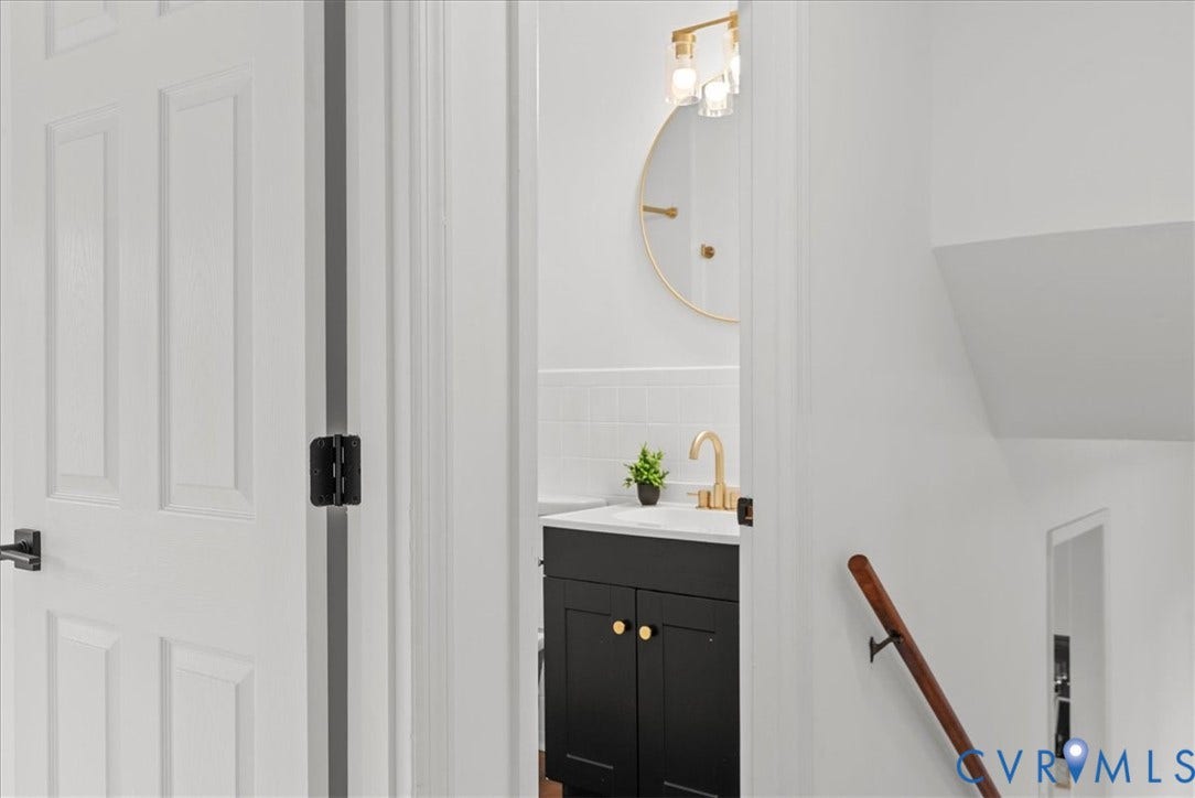 4942 Pleasant Shade Drive, Emporia, Emporia, VA 23847 Bathroom featuring a black vanity with a white countertop, gold-tone fixtures, a circular gold-rimmed mirror, and a wall-mounted wood handrail