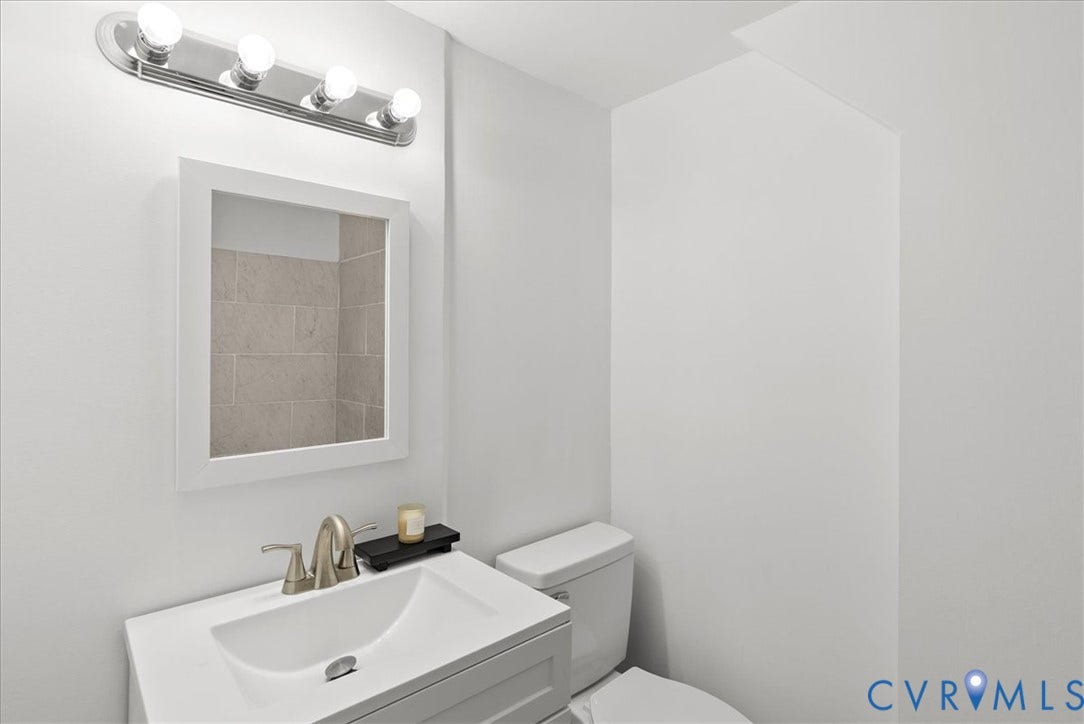 4942 Pleasant Shade Drive, Emporia, Emporia, VA 23847 Wall-mounted four-bulb chrome light fixture, square-framed wall mirror, integrated rectangular sink with a brushed-nickel faucet, and a standard-height toilet