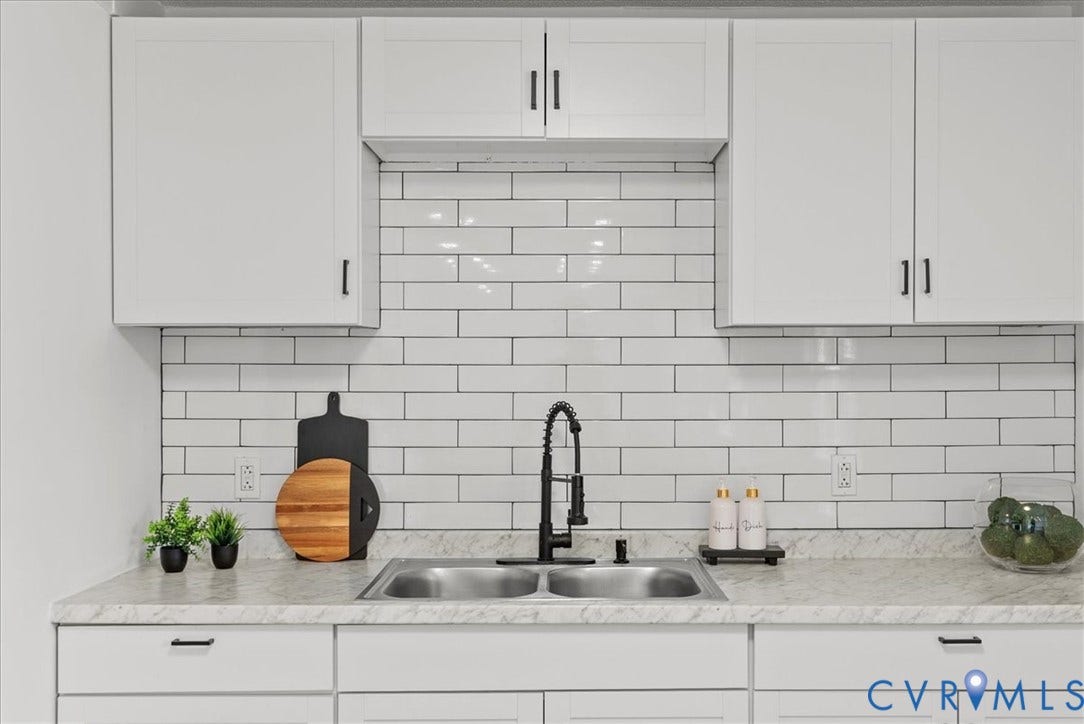 4942 Pleasant Shade Drive, Emporia, Emporia, VA 23847 White shaker-style cabinetry featuring matte black hardware, subway tile backsplash, stone-finish countertop, dual-basin stainless steel sink, and high-arc pull-down faucet