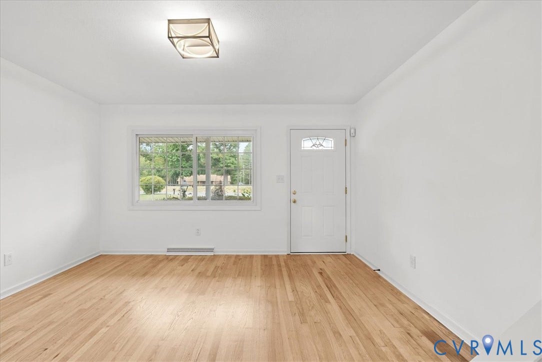 4942 Pleasant Shade Drive, Emporia, Emporia, VA 23847 Room featuring wood-finish flooring, a rectangular sliding window, a single-entry door with a decorative glass insert, and a flush-mount rectangular light fixture