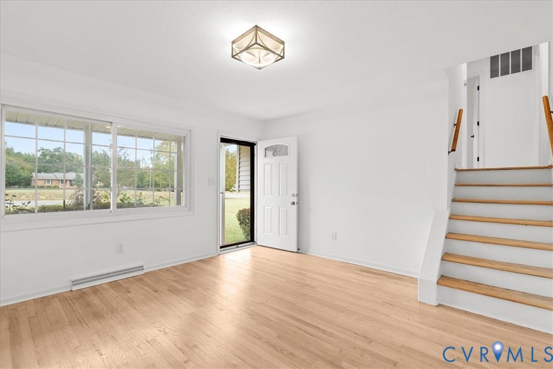 4942 Pleasant Shade Drive, Emporia, Emporia, VA 23847 Interior space featuring wood-finish flooring, a large picture window, a geometric ceiling-mounted light fixture, and a wooden staircase with white risers