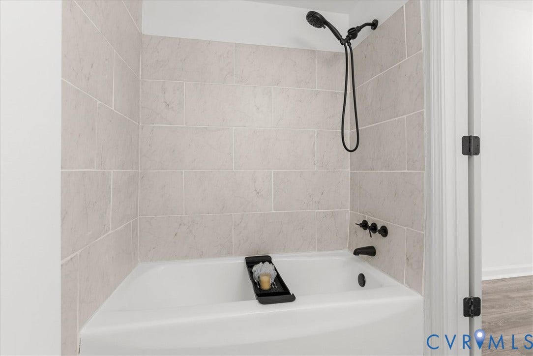 4942 Pleasant Shade Drive, Emporia, Emporia, VA 23847 Bathtub surround featuring light-toned, large-format subway tiles, matte black wall-mounted fixtures, and a handheld showerhead