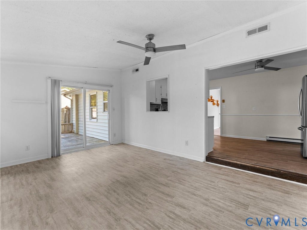 503 Briarwood Circle, Jefferson Circle, North Prince George, VA 23860 Living area featuring wood-finish flooring, a ceiling fan, and sliding glass doors providing outdoor access, with a pass-through opening to a second room finished with wood-finish flooring