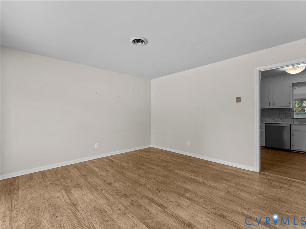 503 Briarwood Circle, Jefferson Circle, North Prince George, VA 23860 Neutral-toned interior featuring wood-finish flooring and a doorway providing a sightline to a kitchen with white cabinetry and stainless steel appliances