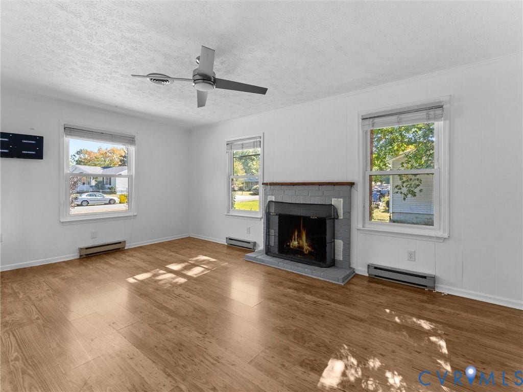 503 Briarwood Circle, Jefferson Circle, North Prince George, VA 23860 Wood-finish flooring, painted brick fireplace with hearth, metal ceiling fan, and large windows providing natural light