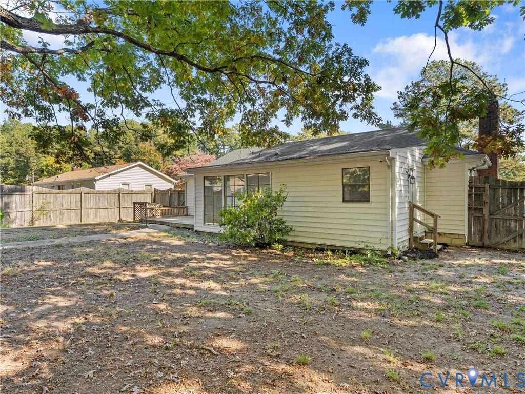 503 Briarwood Circle, Jefferson Circle, North Prince George, VA 23860 Rear exterior featuring horizontal lap siding, an elevated wood deck, a brick chimney, and a full-perimeter wood privacy fence