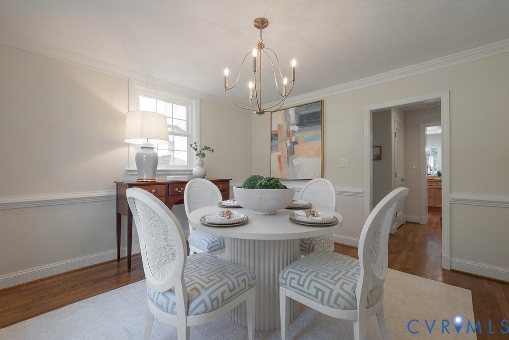 Dining area featuring wood-finish flooring, crown molding, chair rail trim, and a multi-arm metal chandelier