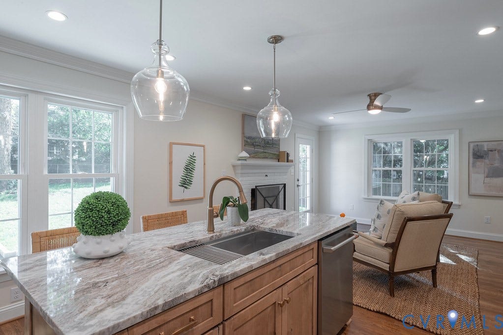 Kitchen island with stone countertop, stainless steel under-mount sink, brass-finish faucet, pendant lighting, and recessed ceiling lights