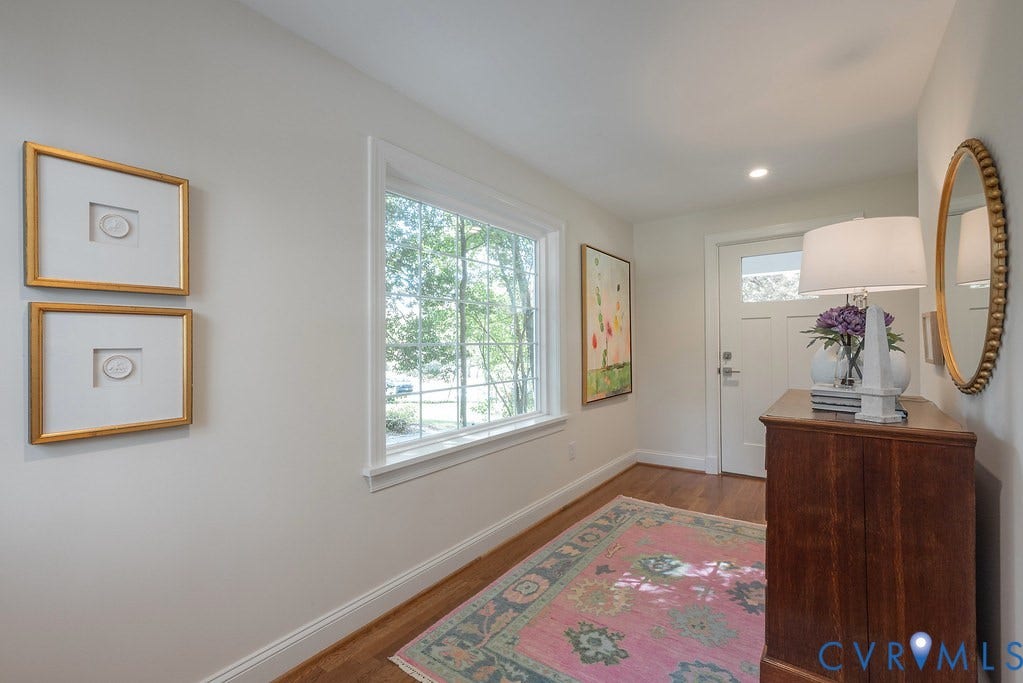 Entry featuring wood-finish flooring, a multi-pane window with wood casing, and a solid-core door with a glass inlay