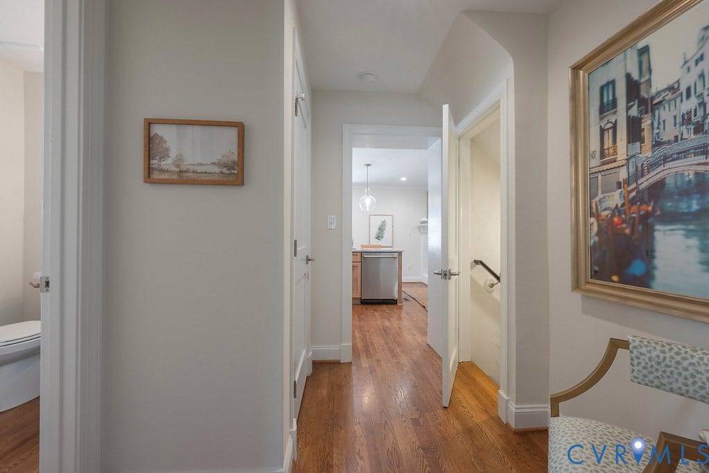 Interior hallway featuring wood-finish flooring, solid-core doors with satin nickel hardware, and neutral wall tones