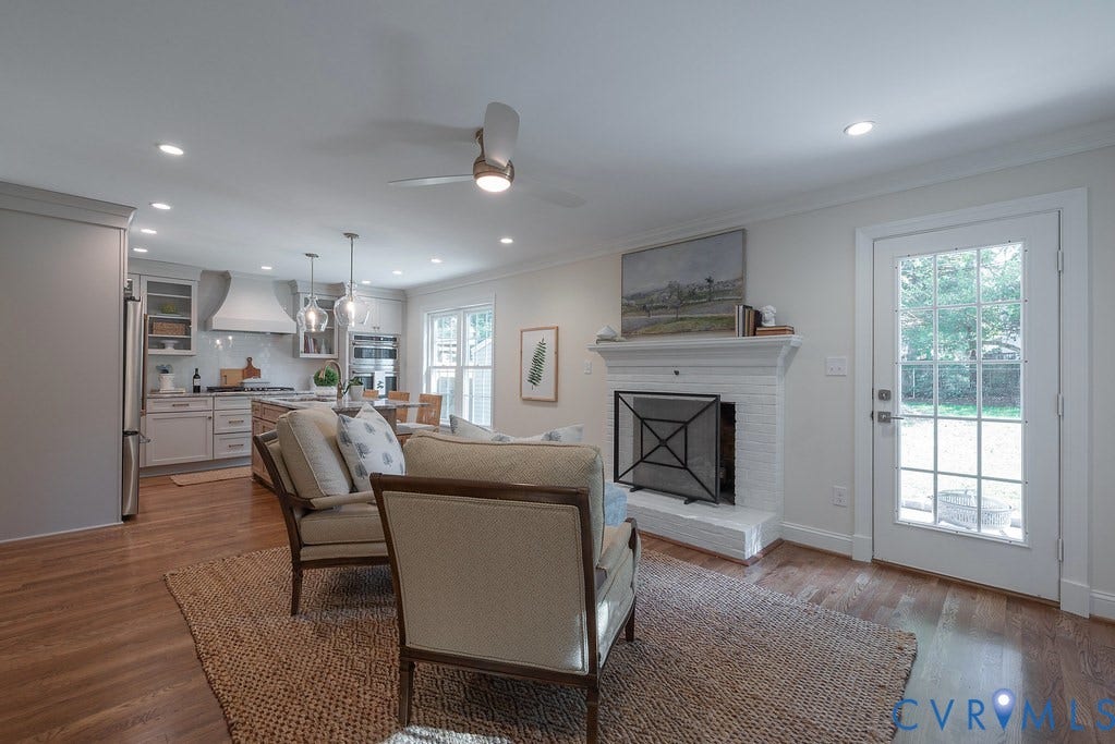 Open-concept interior featuring wood-finish flooring, a white painted brick fireplace, recessed lighting, a modern ceiling fan, and a glass-paneled exterior door