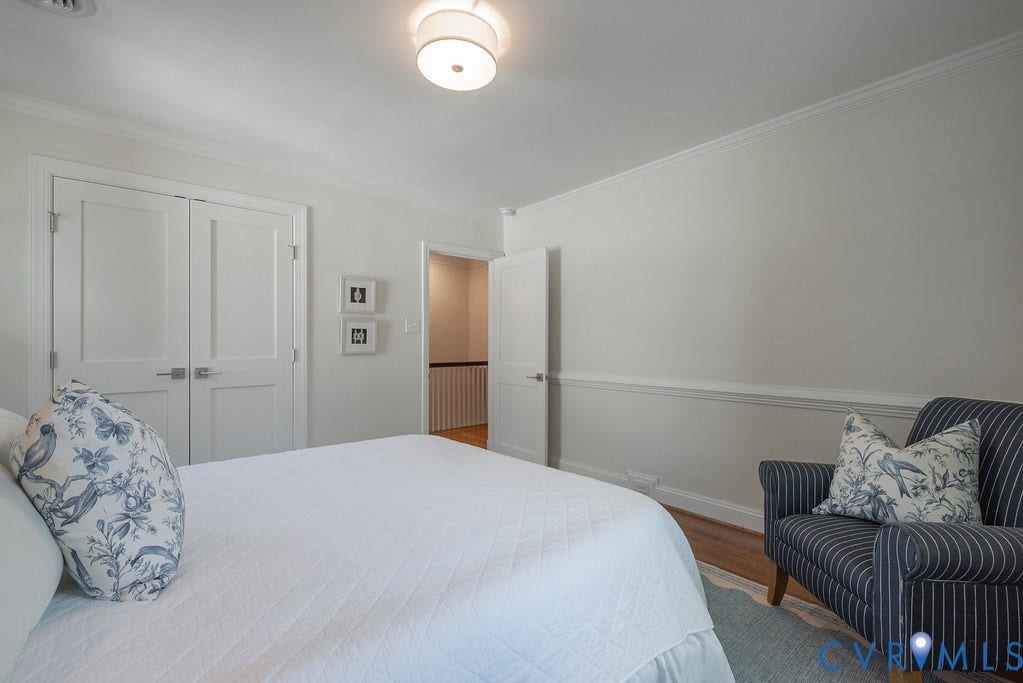 Neutral-toned room featuring crown molding, chair rail trim, wood-finish flooring, double-panel interior doors, and a flush-mount drum light fixture