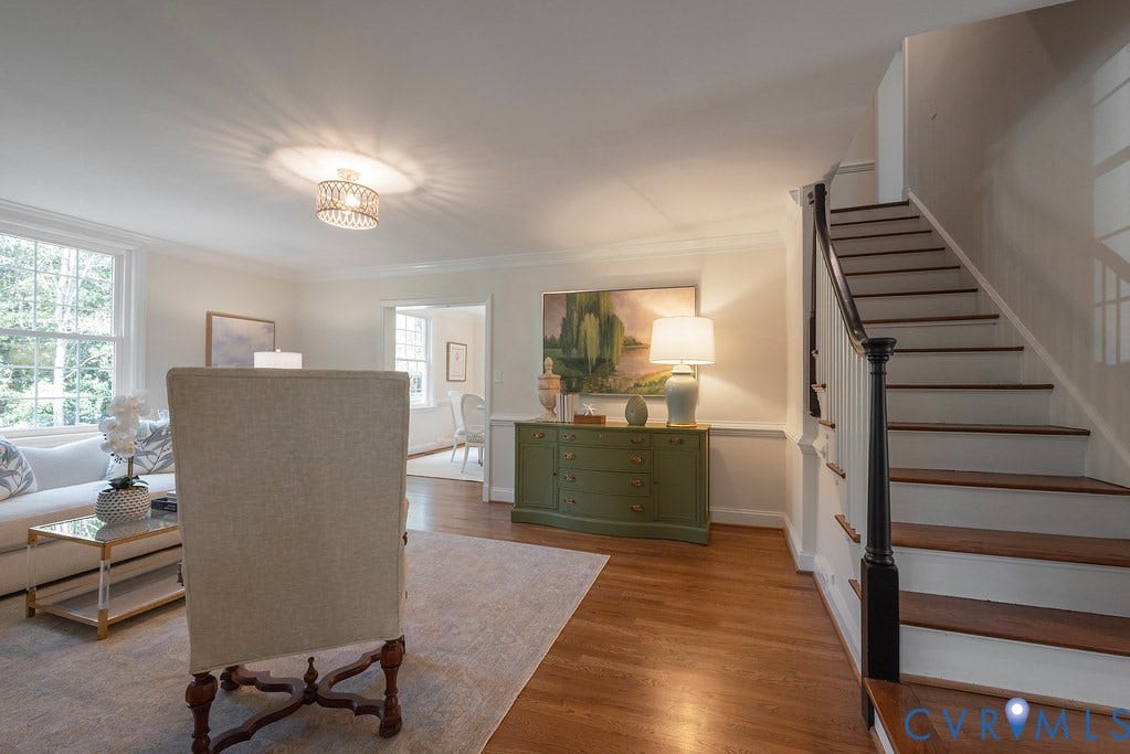 Staircase featuring a dark wood handrail, white balusters, and wood-finish treads, complemented by hardwood flooring, crown molding, chair rail, and a drum-style ceiling light fixture