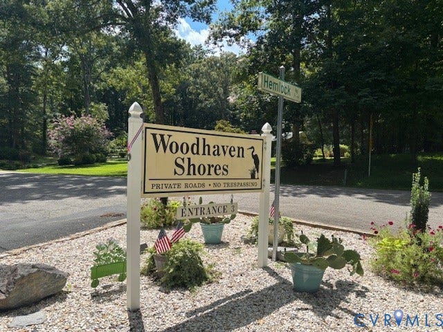 5407 Hemlock Road, Quinton, VA 23141 Woodhaven Shores community entrance featuring signage, paved asphalt roadway, and mature perimeter trees