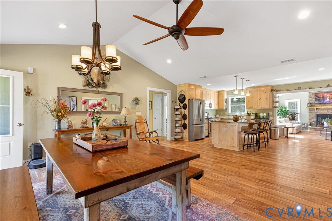 3820 Upshaw Road, Decker's Pond, Aylett, VA 23009 Vaulted ceilings, open-concept kitchen with light wood cabinetry, wood-finish flooring, multi-light chandelier, and stone-surround fireplace