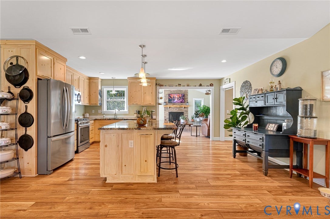 3820 Upshaw Road, Decker's Pond, Aylett, VA 23009 Kitchen featuring light-finish cabinetry, a stone-topped central island with bar seating, stainless steel appliances, and wood-finish flooring