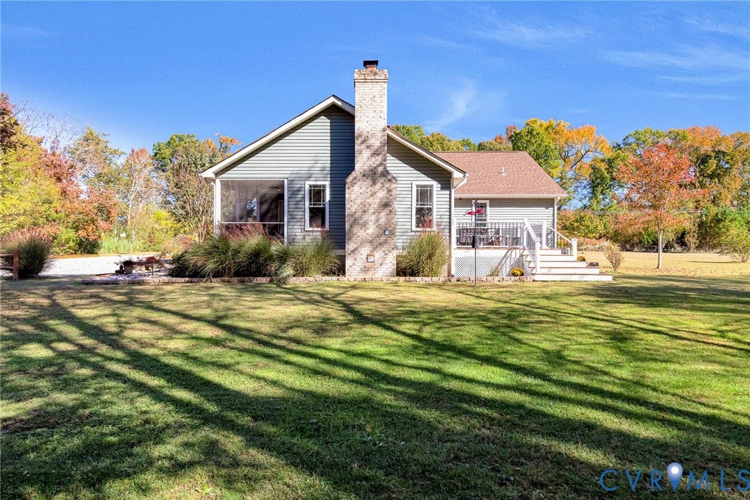 3820 Upshaw Road, Decker's Pond, Aylett, VA 23009 Exterior featuring horizontal siding, a central masonry chimney, a screened porch, a raised deck with staircase, and extensive lawn