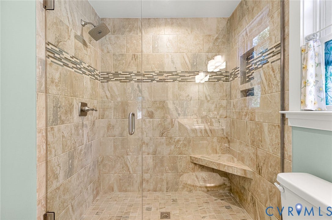 3820 Upshaw Road, Decker's Pond, Aylett, VA 23009 Walk-in shower featuring large-format tile surround, decorative stone mosaic accent border, integrated corner bench, built-in recessed shelf, and glass panel enclosure