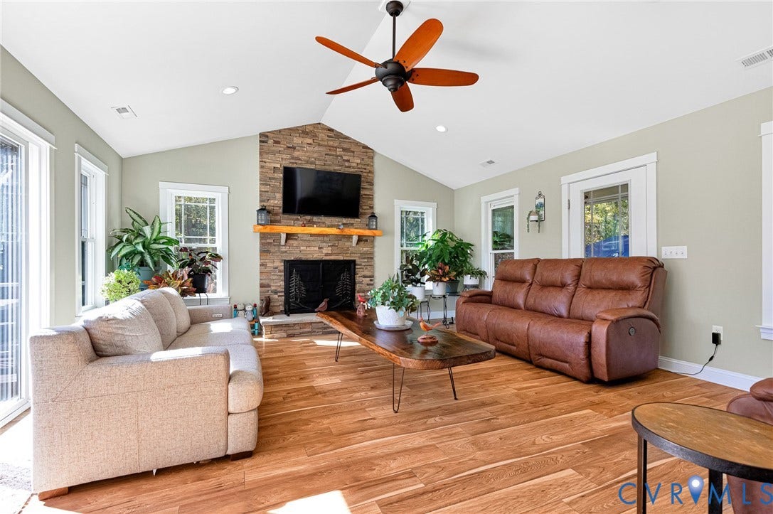 3820 Upshaw Road, Decker's Pond, Aylett, VA 23009 Vaulted ceiling featuring a stacked stone fireplace with a natural wood mantel, wood-finish flooring, and a ceiling fan