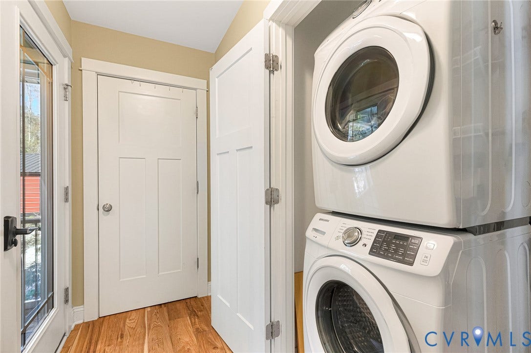 3820 Upshaw Road, Decker's Pond, Aylett, VA 23009 Laundry closet featuring a stackable washer and dryer, wood-finish flooring, and white paneled doors