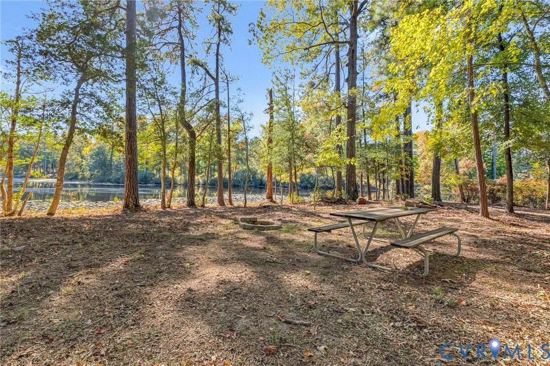 3820 Upshaw Road, Decker's Pond, Aylett, VA 23009 Wooded grounds featuring mature trees, a stone fire pit, and direct shoreline access