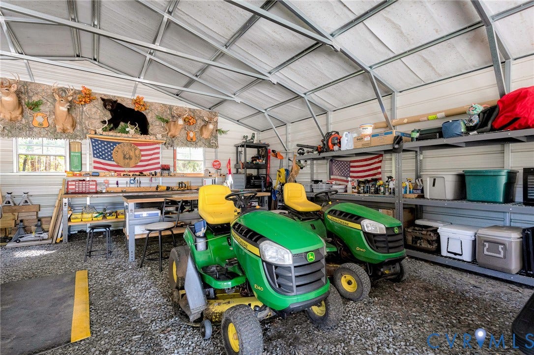 3820 Upshaw Road, Decker's Pond, Aylett, VA 23009 Metal-frame workshop featuring a vaulted roof, gravel flooring, integrated workbench, and fixed metal industrial shelving units