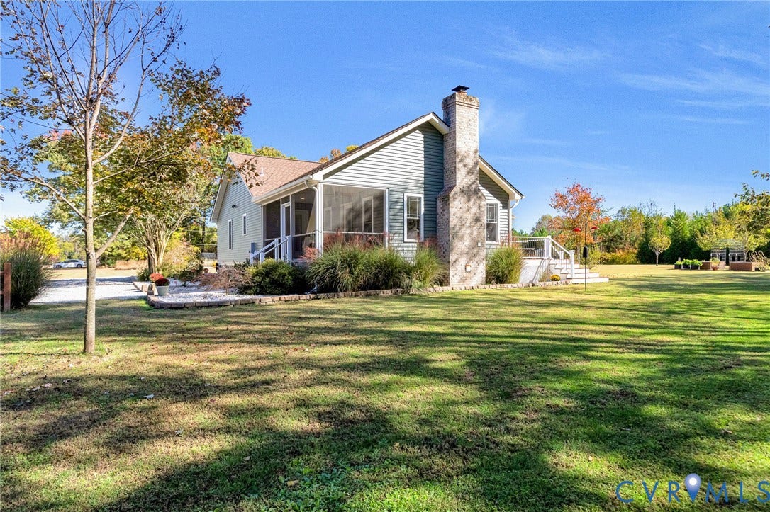 3820 Upshaw Road, Decker's Pond, Aylett, VA 23009 Siding exterior featuring a prominent stone-finish chimney, a screened-in porch, an elevated rear deck with railings, and established landscaping set on expansive grounds