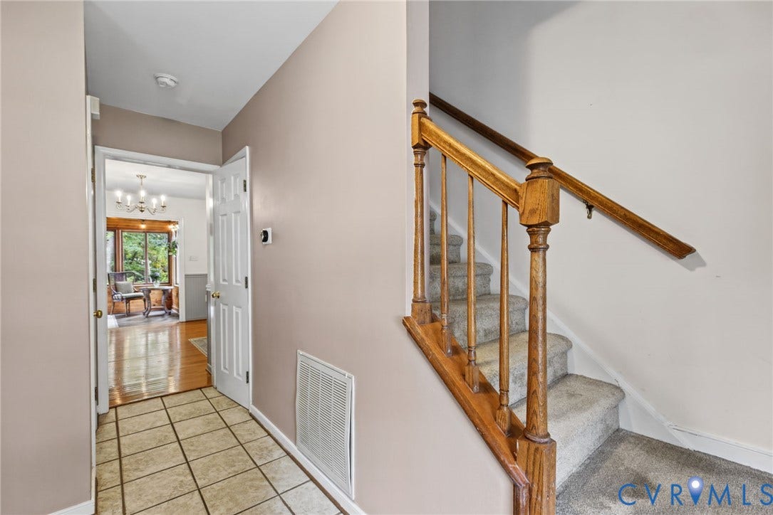 Foyer featuring ceramic tile flooring and a staircase with a stained-wood railing and newel post