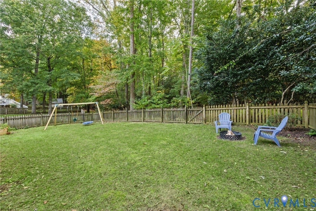 Expansive backyard featuring a fenced perimeter, mature tree canopy, and a grass lawn