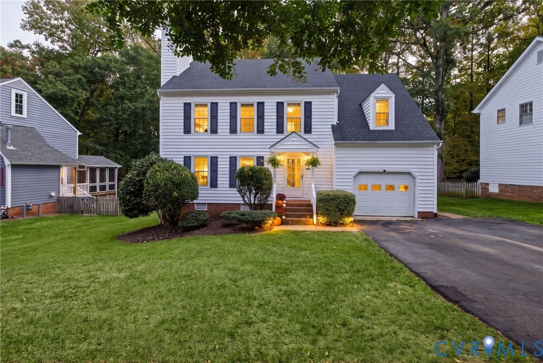 Two-story colonial exterior featuring white siding, dark shutters, a gabled roofline, an attached single-car garage, and an asphalt driveway