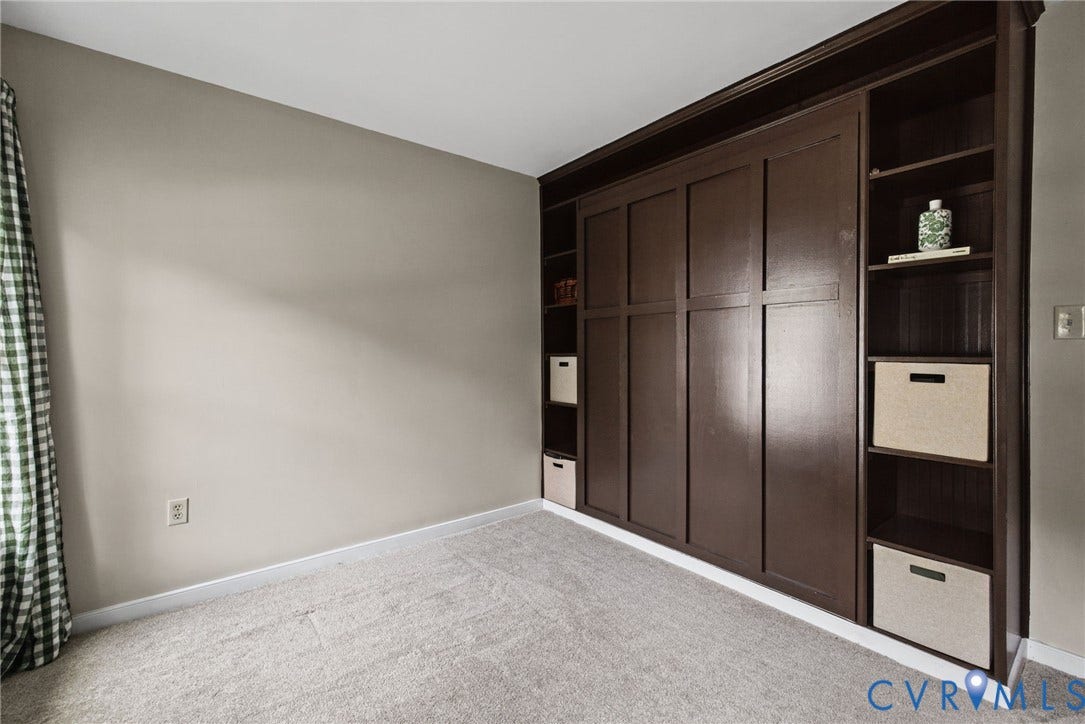 Built-in dark wood cabinetry featuring paneled millwork, open shelving, and integrated storage compartments, complemented by wall-to-wall carpeting