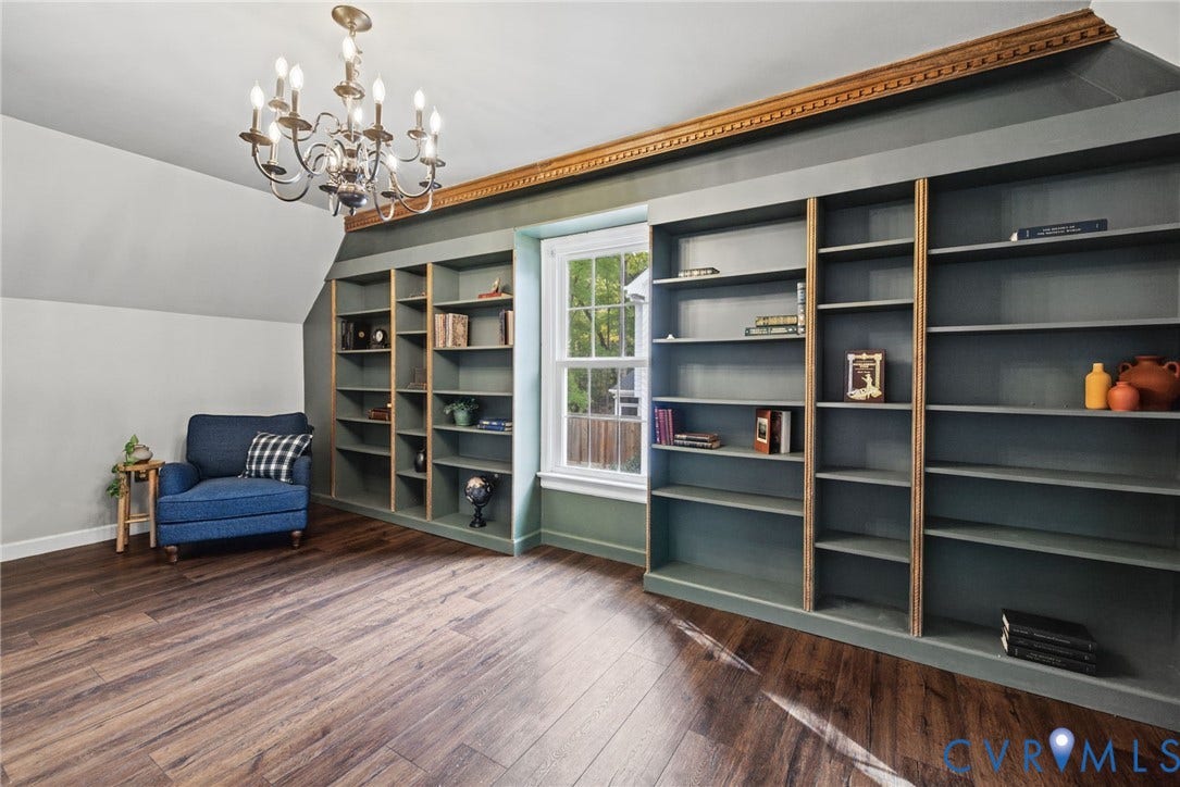 Built-in floor-to-ceiling cabinetry, dark wood-finish flooring, multi-light chandelier, and decorative crown molding