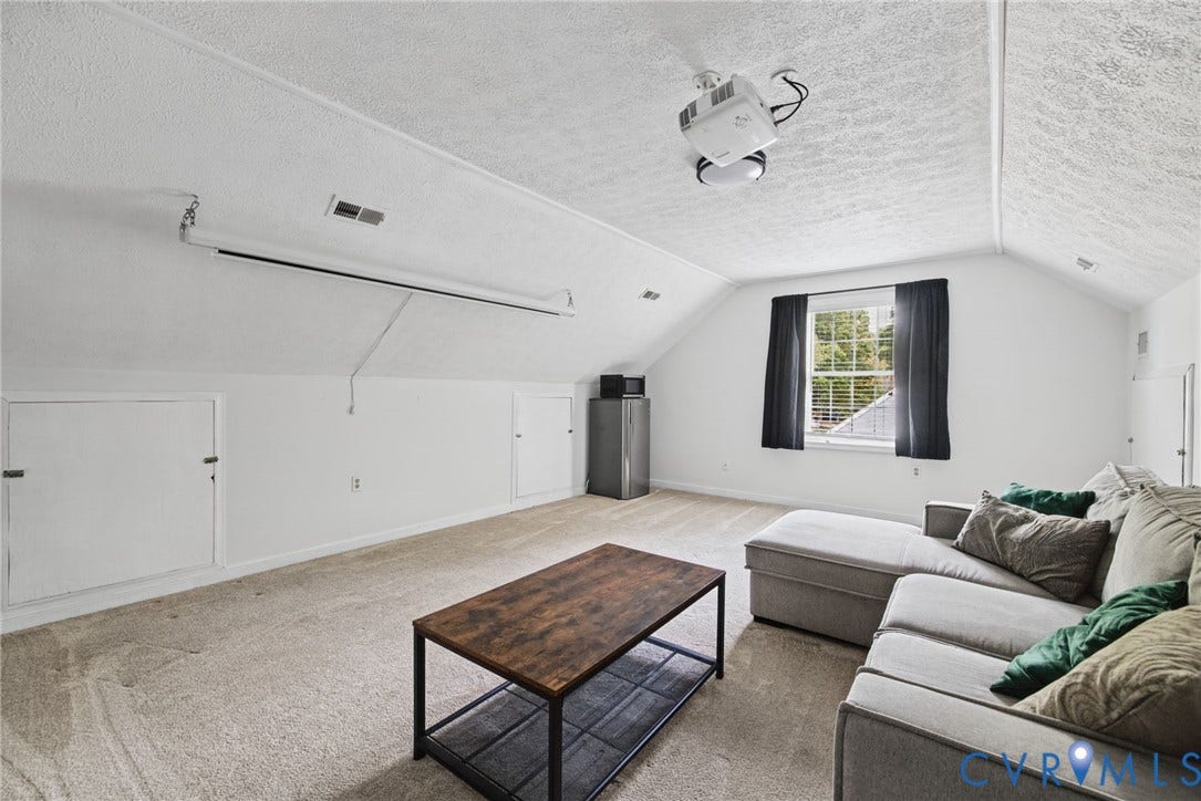 Vaulted ceilings with integrated projector and screen, wall-integrated storage access, and wall-to-wall carpeting