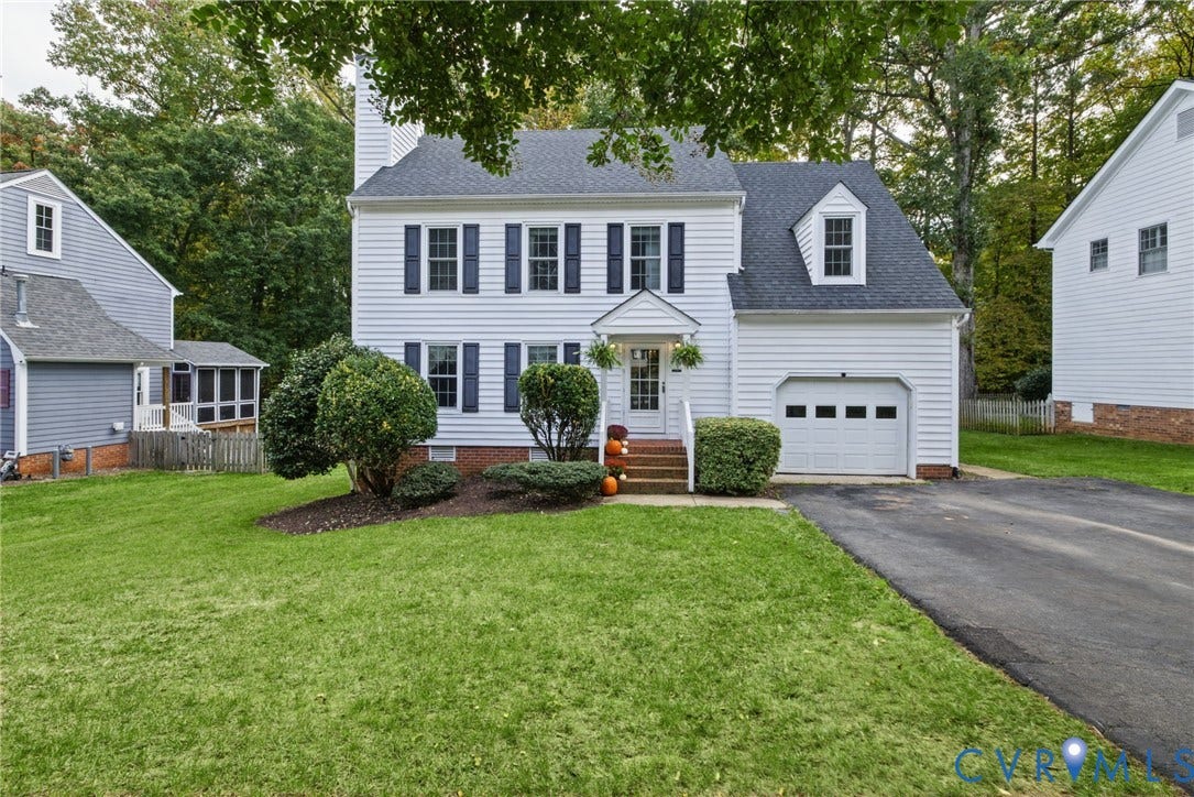 Two-story residence featuring white siding, dark shutters, an attached single-car garage, front dormer window, and an asphalt driveway