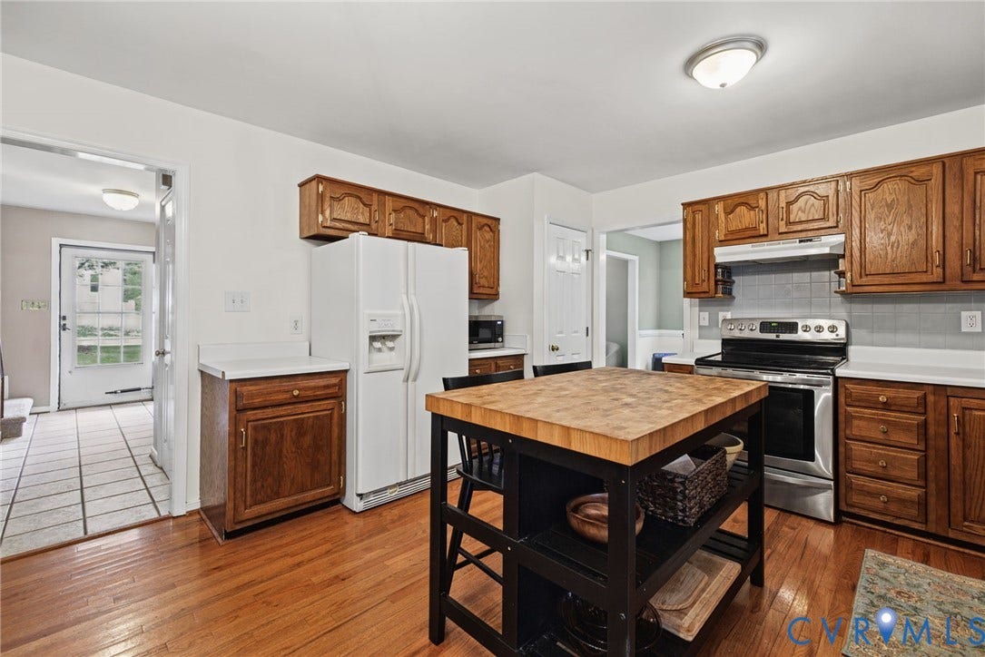 Kitchen featuring wood cabinetry, white countertops, wood-finish flooring, and stainless steel range