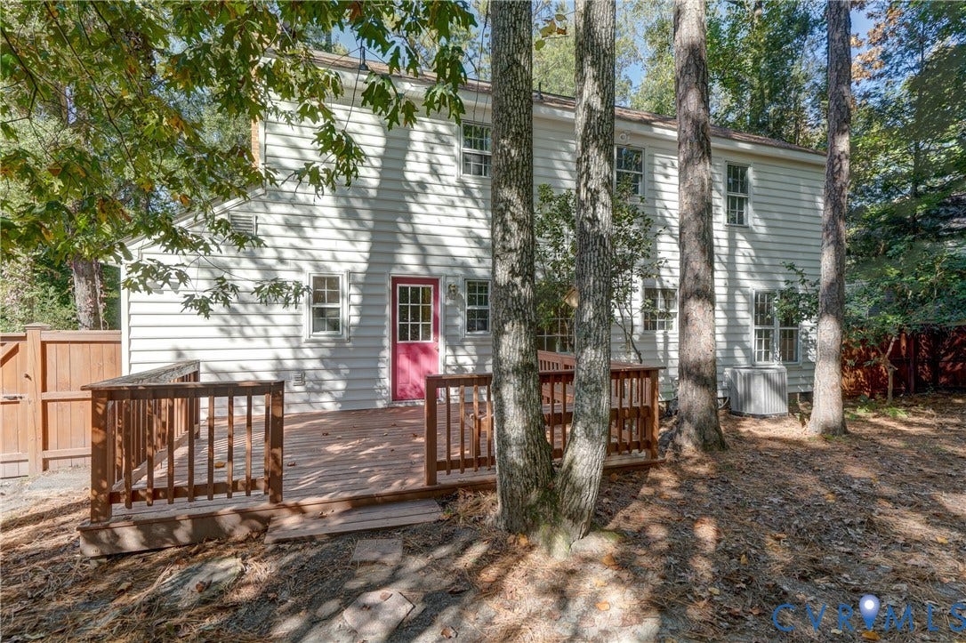 5 Bridgehampton Place, Yorkshire, Henrico, VA 23229 Exterior elevation featuring horizontal siding, a multi-lite door, and an elevated wood deck enclosed by a wood railing, situated on a lot with mature trees and wood perimeter fencing