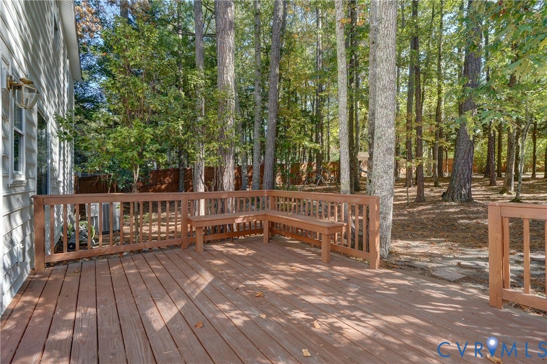 5 Bridgehampton Place, Yorkshire, Henrico, VA 23229 Raised wood-plank deck featuring built-in bench seating, wood railing, exterior wall-mounted light fixture, and wooded surroundings