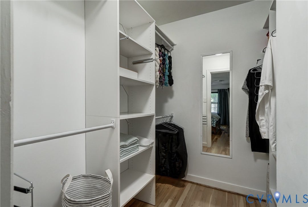5 Bridgehampton Place, Yorkshire, Henrico, VA 23229 Walk-in closet featuring white built-in shelving, vertical storage compartments, dual-level hanging rods, and a wall-mounted mirror over wood-finish flooring