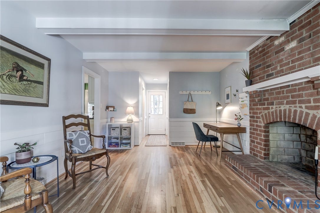 5 Bridgehampton Place, Yorkshire, Henrico, VA 23229 Living area featuring a floor-to-ceiling brick fireplace with a raised brick hearth, exposed ceiling beams, horizontal wainscoting, and wood-finish flooring