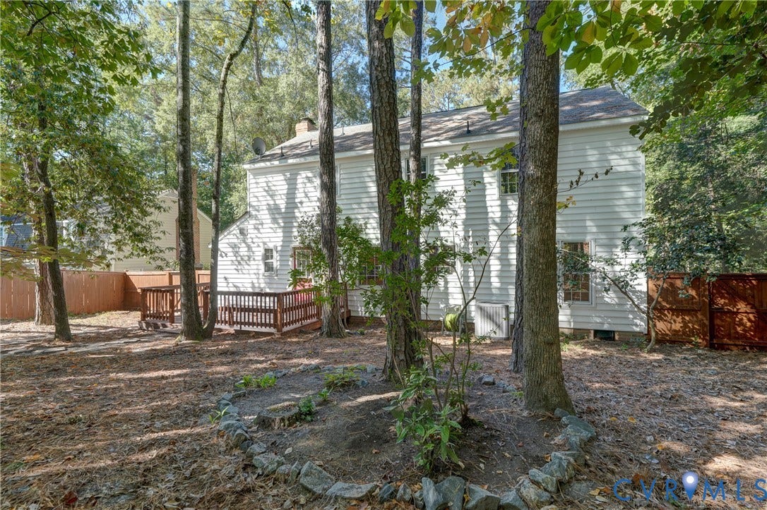 5 Bridgehampton Place, Yorkshire, Henrico, VA 23229 Two-story residence with white siding, rear wooden deck, stone-bordered landscaping, and wood privacy fencing